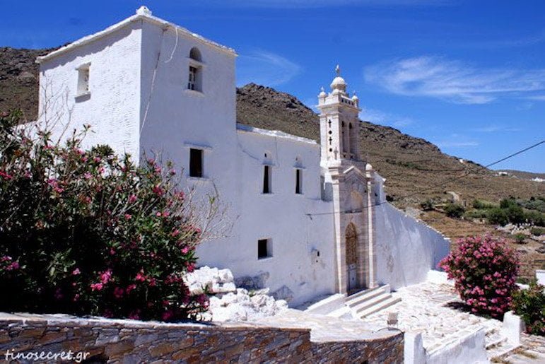 Tinos, Marlas, Festival of Kyra Xeni - Gastronomy Tours front of church of Kyra Xeni, in Tinos, Greece that commemorate festival of her birth, surrounded by hills and trees with red flowers